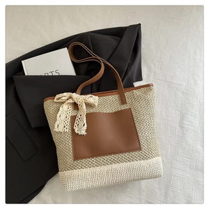 Detailed texture of woven straw tote bag with brown leather pocket and white lace bow