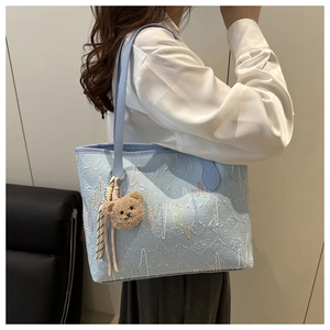 Light blue tote bag with letter embossing, wavy embroidery and a cute bear charm