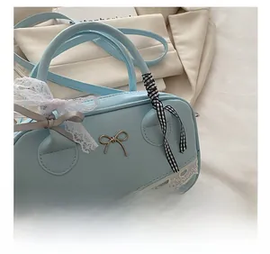 Detail shot of light blue lace Boston bag featuring gold bow and floral ribbon decor
