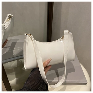 Close-up of a white patent leather baguette bag with a glossy finish and gold zipper