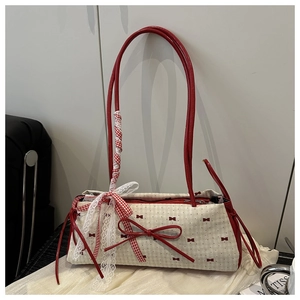 Détail du sac en toile crème avec motifs de nœuds rouges et rubans en dentelle