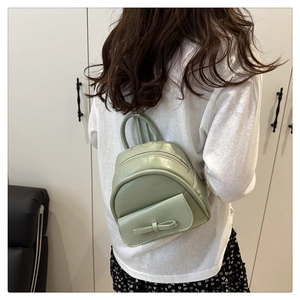 Back view of a mini mint green leather backpack with a decorative bow on white background