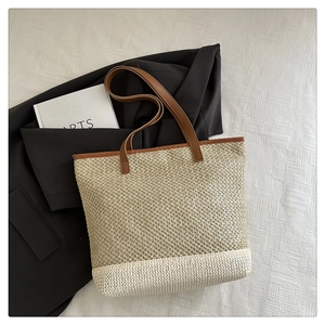 Detailed close-up of woven straw tote bag featuring two-tone contrast and leather handles