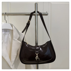 Detailaufnahme der dunkelbraunen glänzenden Schultertasche aus Leder mit goldener Schnalle