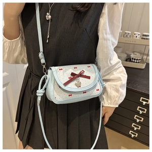 Détail du sac bleu clair avec imprimés nœuds rouges et pendentif cœur en métal