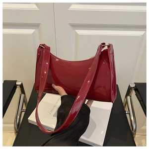 Macro shot of glossy burgundy patent leather shoulder bag with smooth mirrored finish