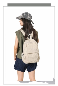 Side view of cream white nylon backpack with multi-pockets and adjustable black buckles
