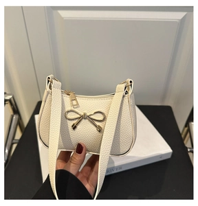 Détails de la texture blanche à motif litchi et du nœud doré sur le sac à main chic