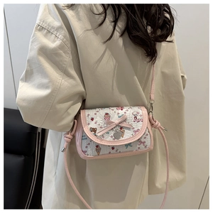 Détail du sac bandoulière rose avec imprimés ours et un pendentif coeur en métal