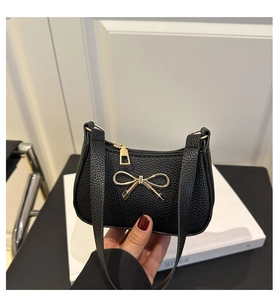 Détail d'un sac à main noir en cuir texturé litchi avec un décor de nœud doré élégant