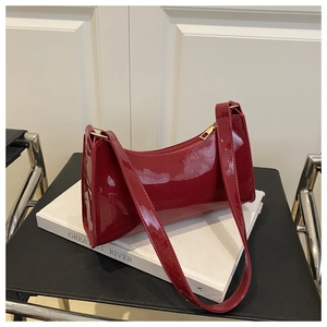 Detail of glossy wine red patent leather baguette bag with premium golden zipper closure