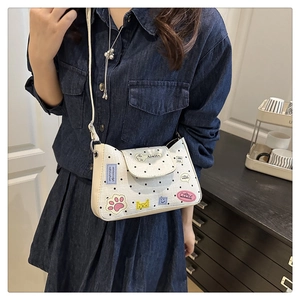Close-up of white polka dot tote bag with colorful cartoon patches and slim shoulder strap
