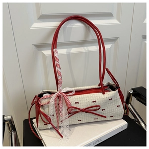 Détail du sac à bandoulière beige avec motif nœud rouge et bordure en dentelle blanche
