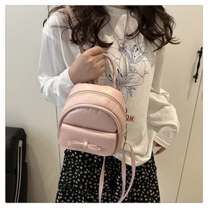 Detailed view of mini pink shell backpack with ribbon bow and dual zipper texture