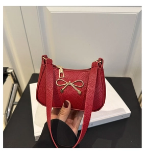 Gros plan du sac à main en cuir grainé rouge avec un fermoir nœud doré élégant