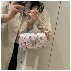 Détail du sac blanc à motifs cartoon avec nœud rose et breloque en cœur