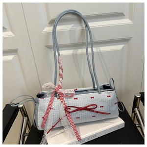 Détail d'un sac à main bleu clair à carreaux avec nœuds rouges et ruban en dentelle
