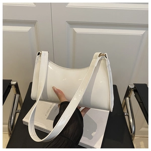 Detailed view of a white patent leather baguette bag with matching wide shoulder strap
