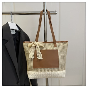 Detail of woven straw tote bag with leather straps, lace bow, and bicolour bottom design