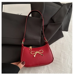 Gros plan du sac à main rouge en cuir grainé avec un détail de nœud doré fin
