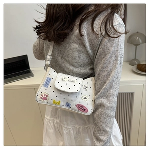 Detail of white polka dot shoulder bag with cute cartoon patches and adjustable strap