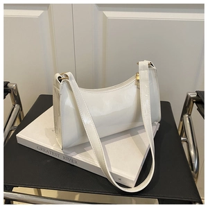 Close-up of white patent leather shoulder bag with smooth curves and golden zipper detail
