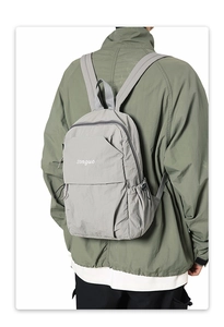 Detail of grey nylon backpack with white songuo print and zipper closure on back