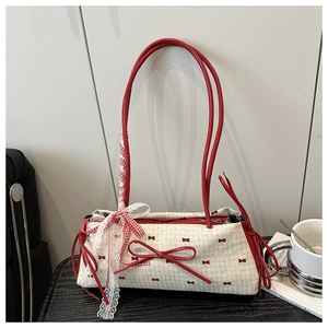 Détail du nœud laqué rouge et du ruban de dentelle à carreaux sur le sac en toile beige