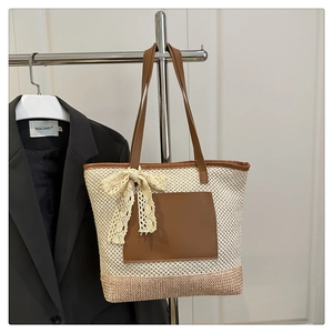 Detail of beige straw tote bag with brown leather pocket and elegant lace bow decoration
