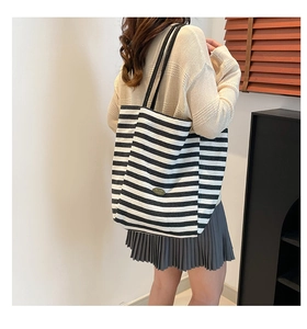 Detailaufnahme der gestreiften Canvas-Tasche mit Metall-Logo und stabilen Tragegurten