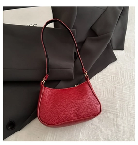Détail du sac sous le bras en cuir rouge grainé avec finitions dorées et zip
