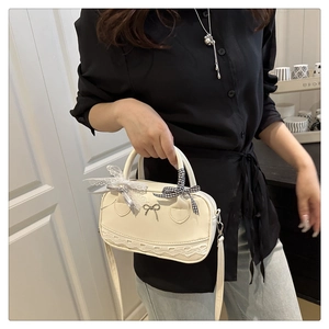 Detail of cream white mini Boston bag with lace trim and checkered bow accent
