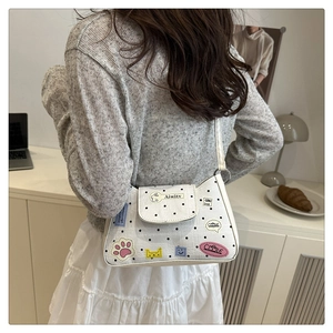 Detail of white polka dot tote bag with cartoon embroidery worn over shoulder