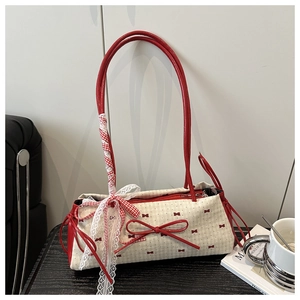 Détail du sac à nœud crème avec ruban en dentelle rouge sur bois noir