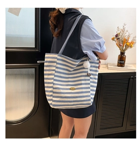 Sac fourre-tout en toile à rayures bleues et blanches avec pompon porté à l'épaule