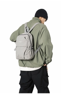 Detail of light grey waterproof nylon backpack showing side pocket and texture on a model