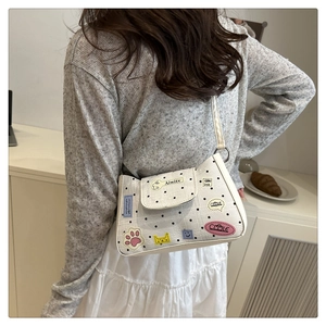 Detail of white polka dot tote bag with colorful cartoon patches and magnetic flap closure