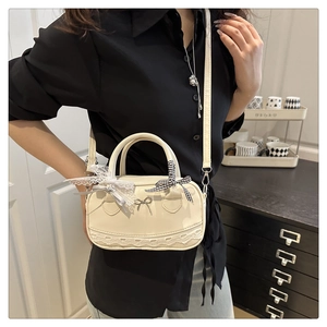 Dettaglio borsa a mano color crema stile balletto con pizzo e fiocco sul davanti