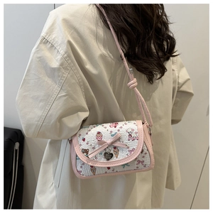 Détail d'un sac bandoulière blanc avec nœud rose et motifs de dessins animés sur modèle