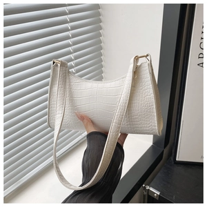 Detail of white crocodile embossed texture on a baguette bag with gold metal buckle