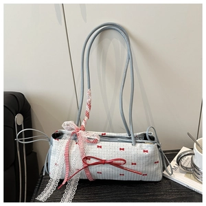 Détail du sac sous le bras bleu avec motifs nœuds rouges et rubans en dentelle