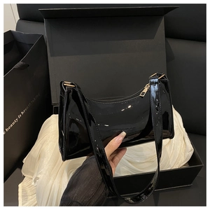 Close-up of black patent leather shoulder bag with gold zipper in luxury gift box