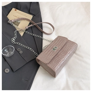 Borsa a tracolla rosa stampa coccodrillo con chiusura argentata su blazer grigio