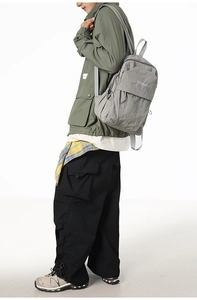 Side view of a grey large-capacity nylon backpack worn by a model in a studio