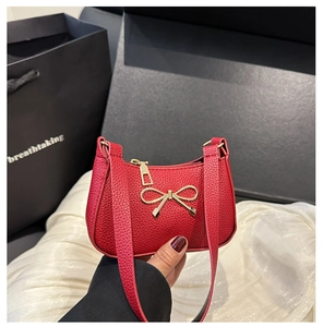 Détail d'un sac en cuir grainé rouge avec un élégant nœud métallique doré raffiné