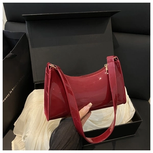 Macro shot of wine red patent leather shoulder bag with golden zipper and premium texture