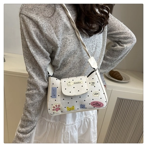 Polka dot white crossbody bag with cartoon stickers worn with a grey knit top