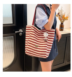 Detail der rot gestreiften Canvas-Tasche mit Leder-Patch und Plüsch-Anhänger