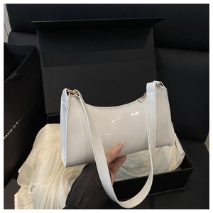 Detail of white patent leather baguette bag with high-gloss finish and gold hardware