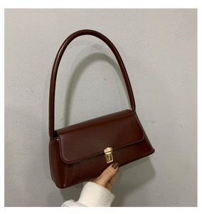 Détail du sac bandoulière en cuir bordeaux avec un élégant fermoir en métal doré